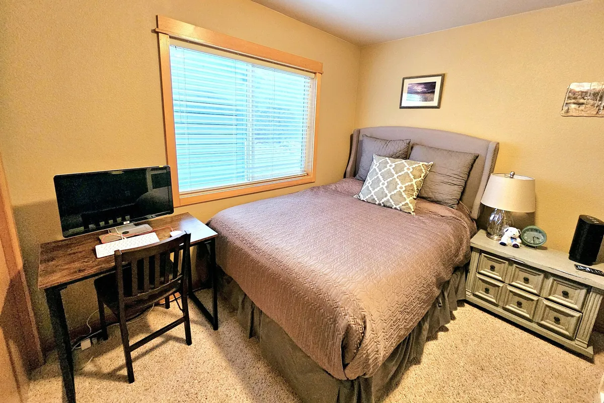 A cozy, functional workstation space with a desk, computer, lamp, and window, creating an ideal nook for productivity or remote work, yet still visually integrated into a home setting.