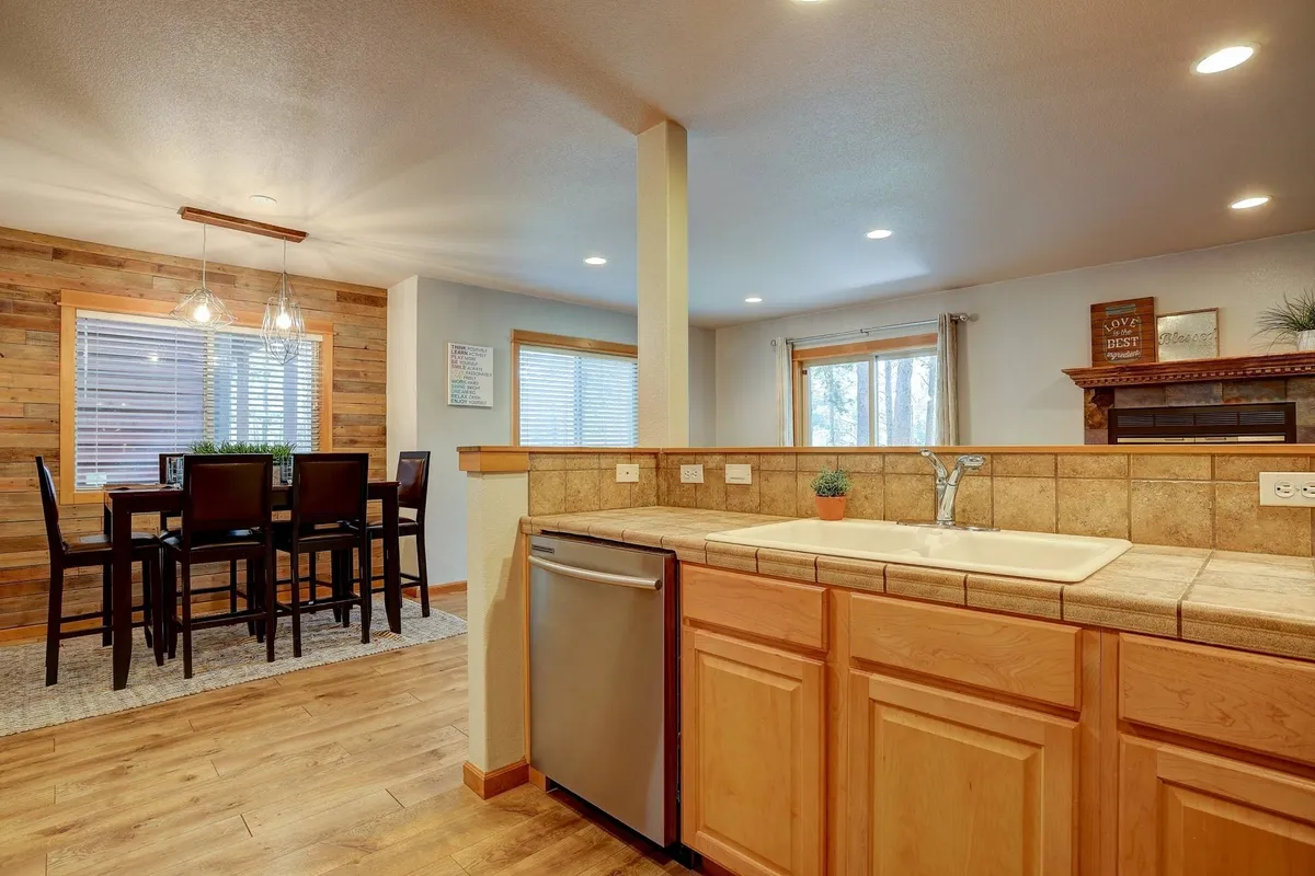 A warm and welcoming interior with a spacious kitchen counter and dining table set against a wooden wall. The scene captures a gathering place perfect for sharing meals, socializing, and creating memories together.
